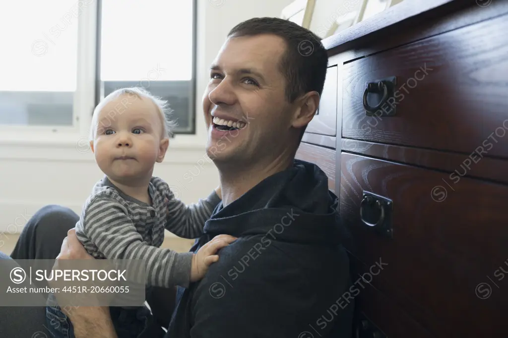 Laughing father holding baby son