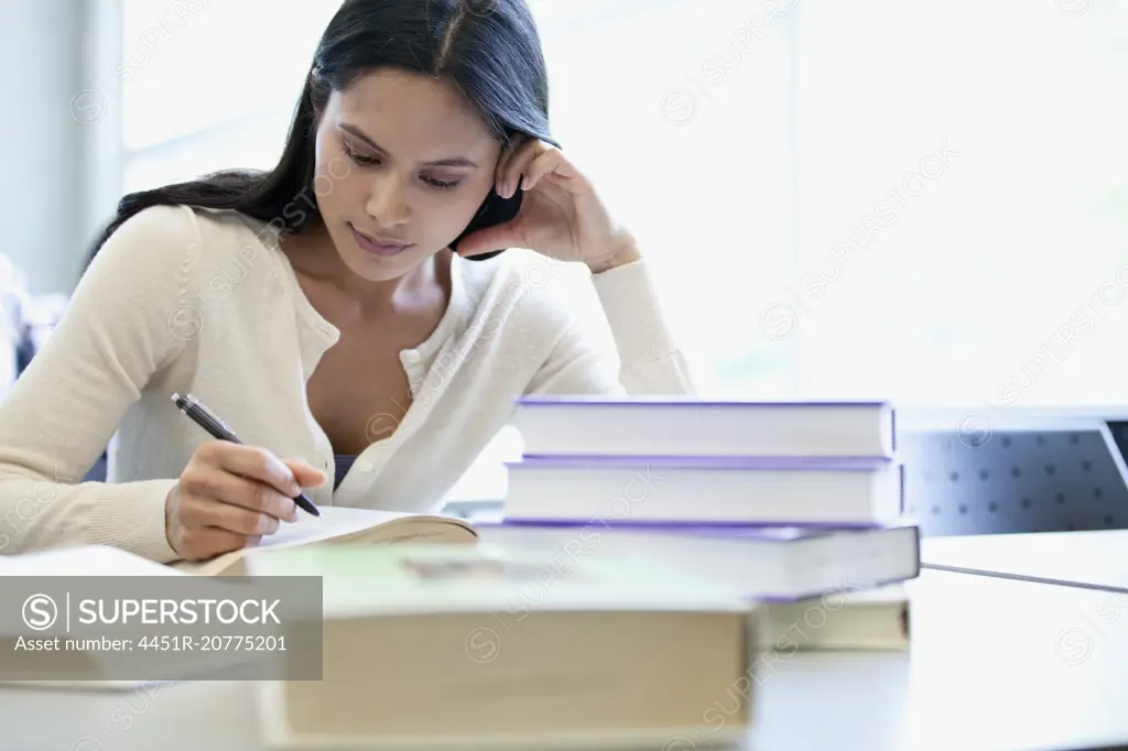 female college student writing paper in classroom