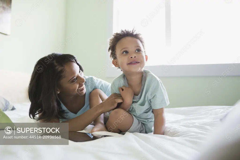 Playful mother with baby on bed at home