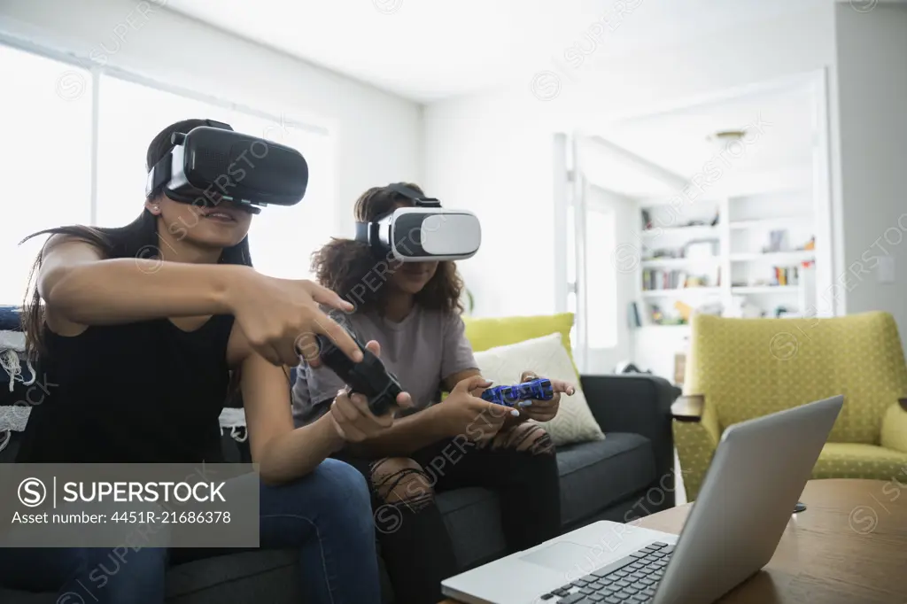 Teenage girl friends playing video games with virtual reality simulators in living room