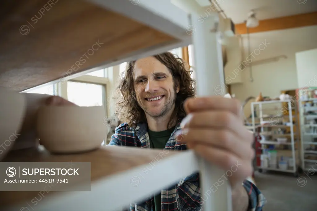 Pottery technician pushing shelf in pottery studio