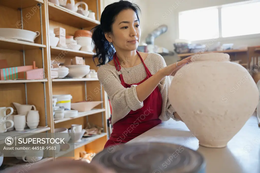 Female potter examining pot in studio