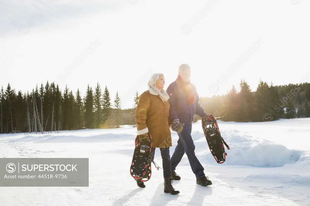 Couple carrying snowshoes outdoors