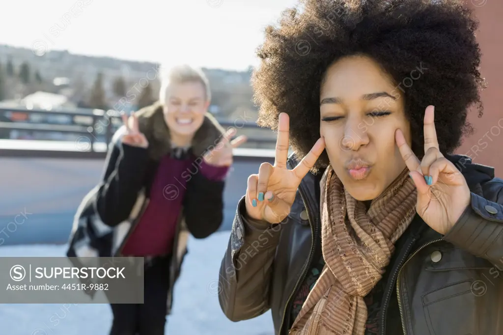 Playful woman showing peace sign outdoors