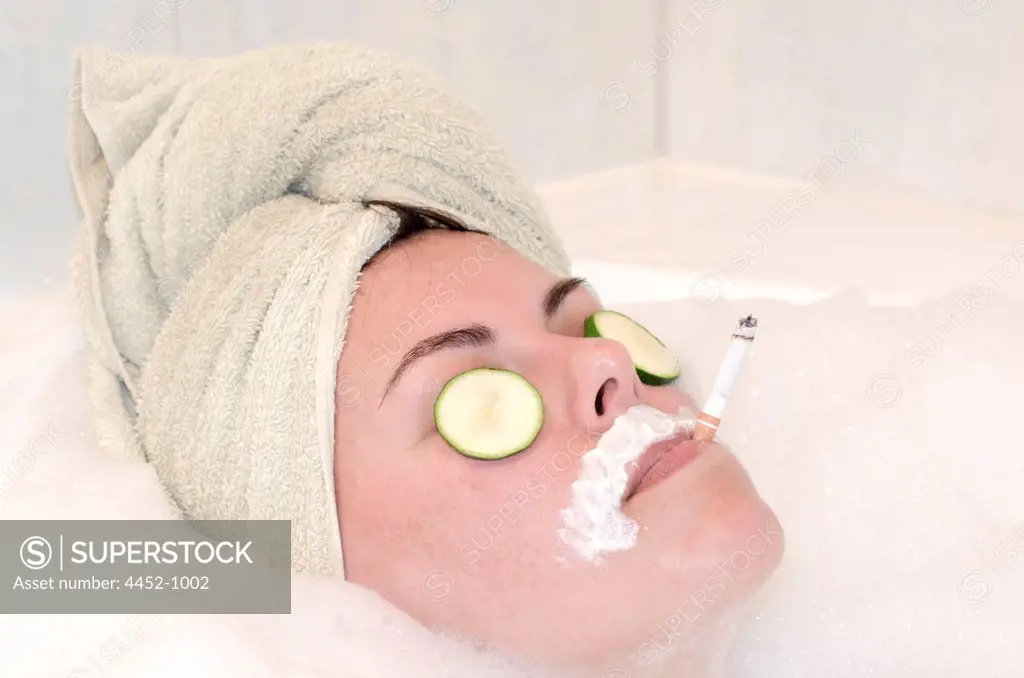 Woman Relax in Bathtub with Cucumber on Her Eyes and Smoking.