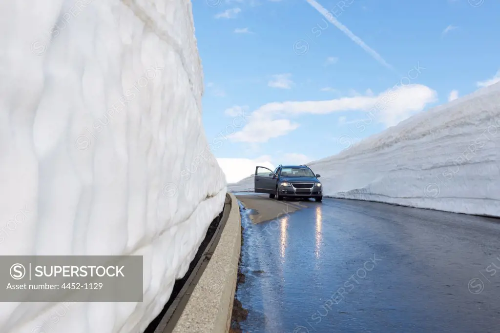 Car on a Mountain Road with Snow Wall on the Road in San Gottardo Pass in Switzerland.