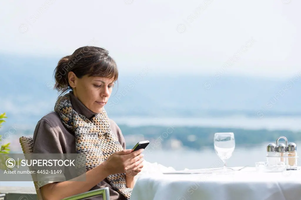 Woman Sitting in a Restaurant and Using Her Phone in Switzerland.