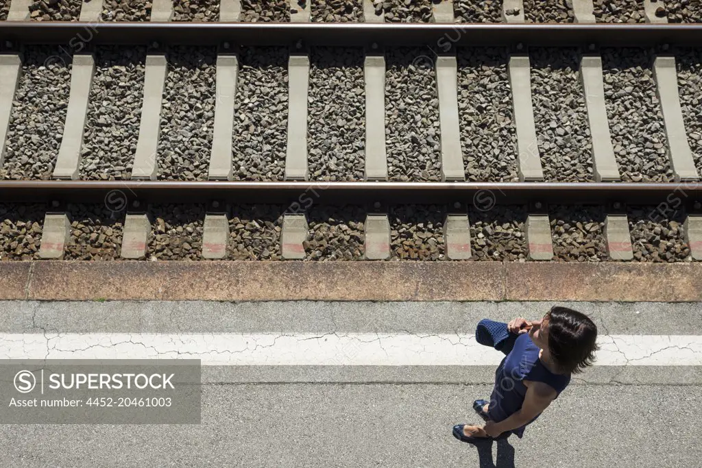 Aerial View of a Woman Waiting on Railroad Station with Tracks in Bellinzona, Switzerland.