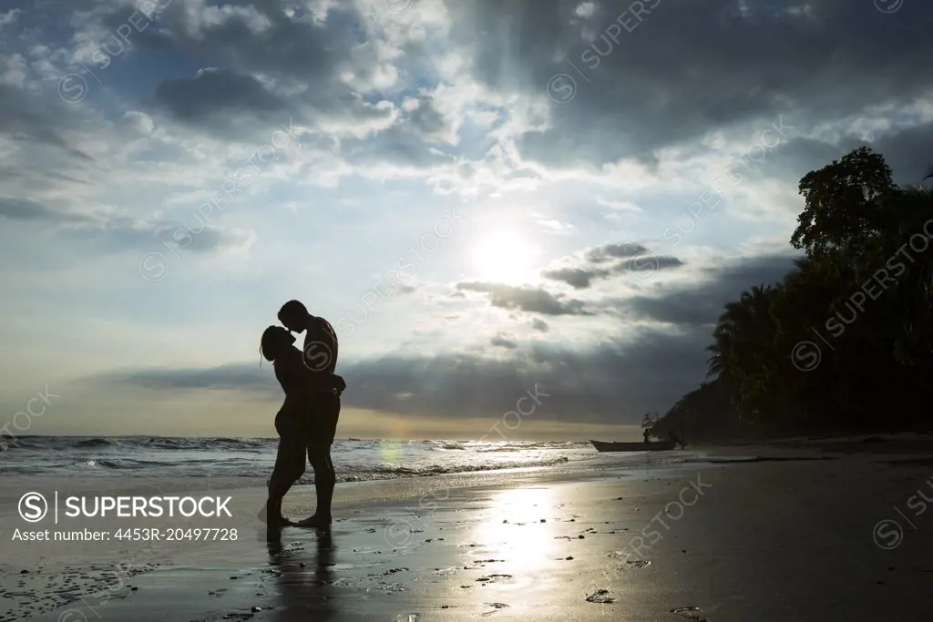 Couple hugging on tropical beach at sunset