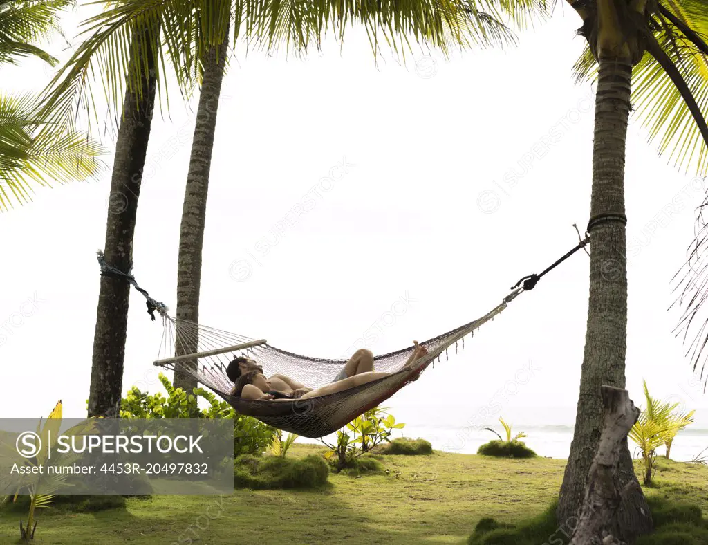 Couple sleeping in hammock on tropical beach