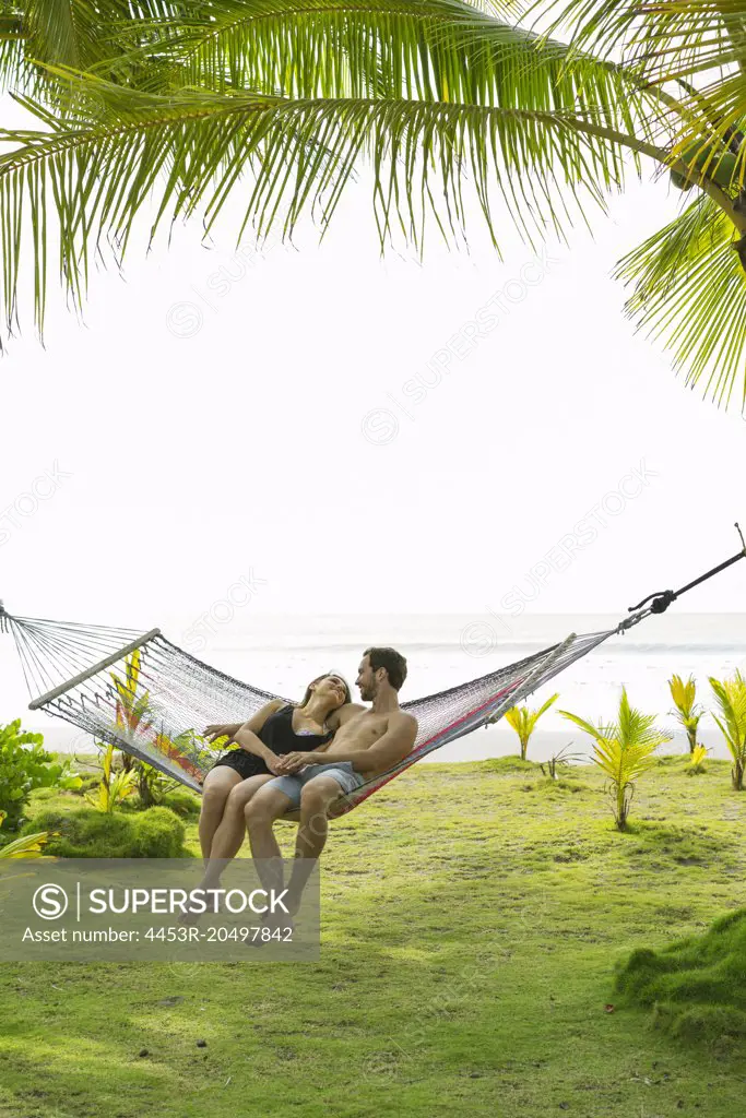 Couple laying in hammock on tropical beach