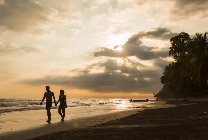 Couple walking on tropical beach at sunset