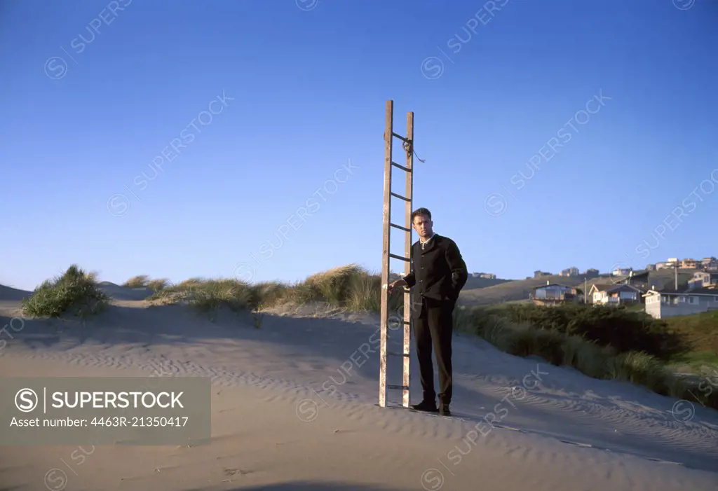 Man standing on beach with ladder