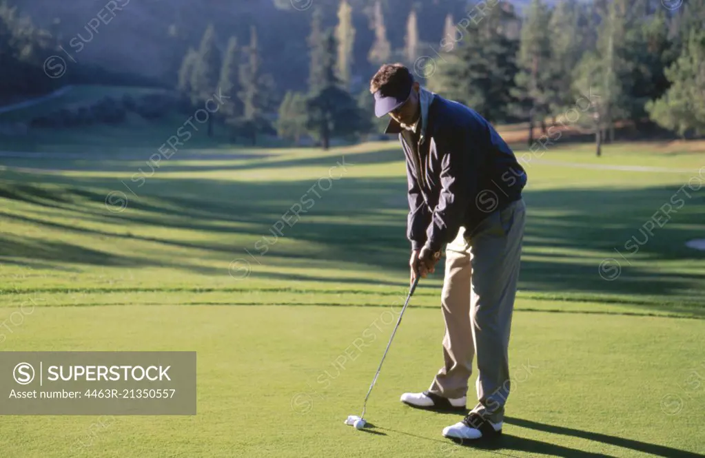 Young man preparing to hit a golf ball on a golfing green.