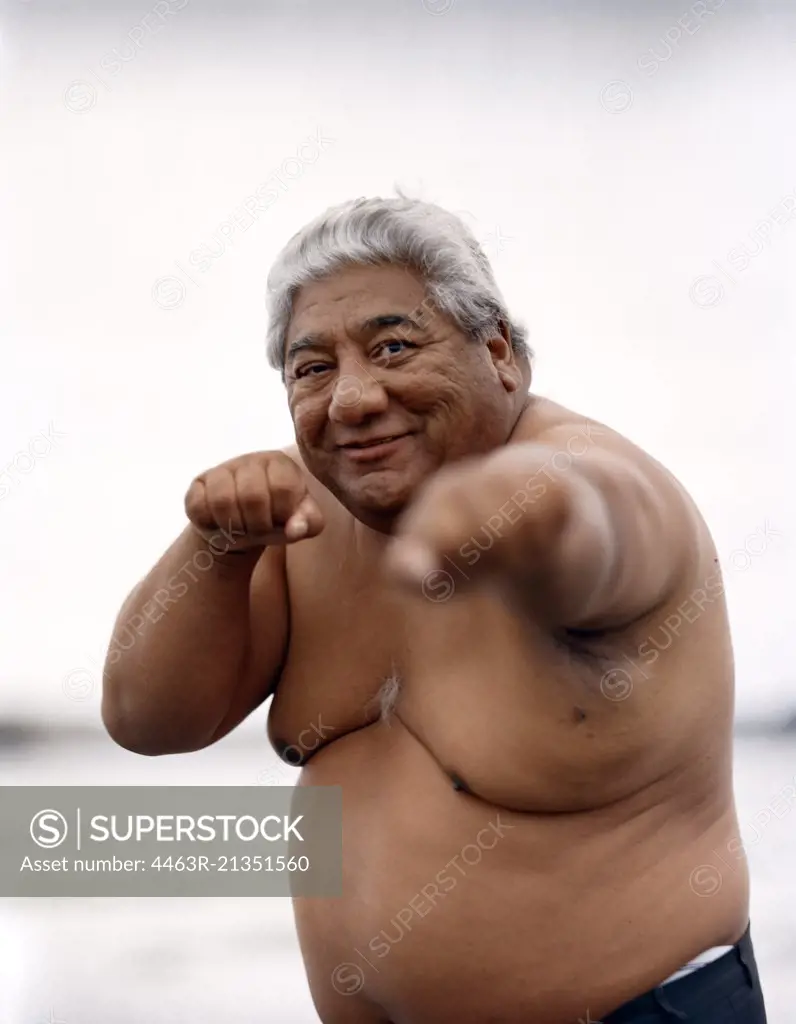 An obese old man throwing a punch.