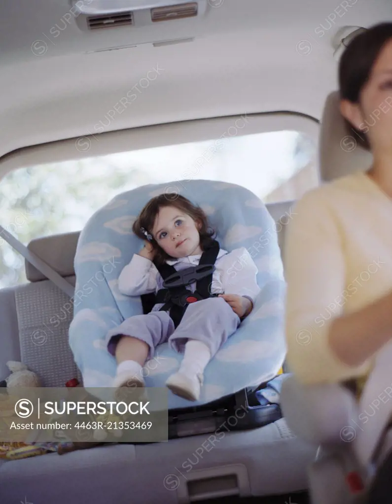 Young girl sitting in a car seat in the back of her mother's car.