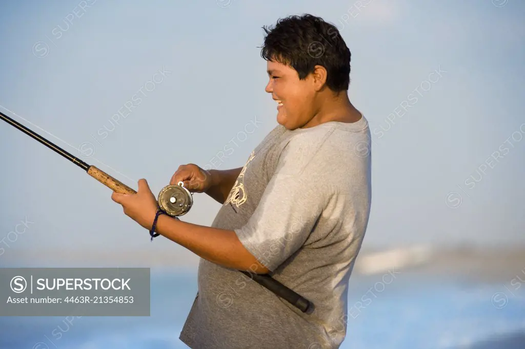 Portrait of a fat boy fishing near the sea.