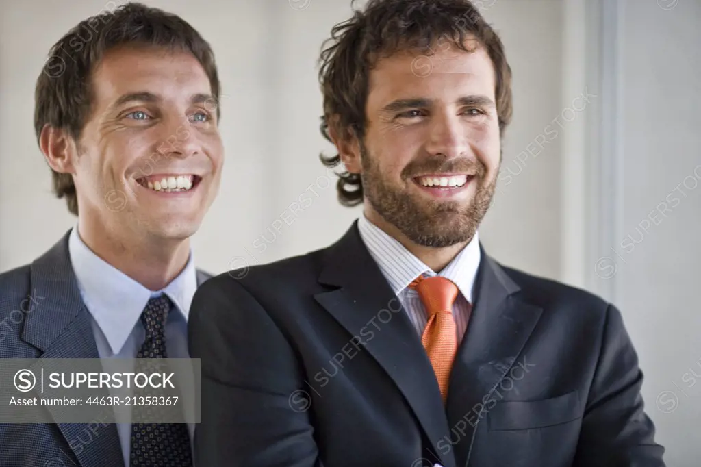 Two smiling young adult business men in an office.