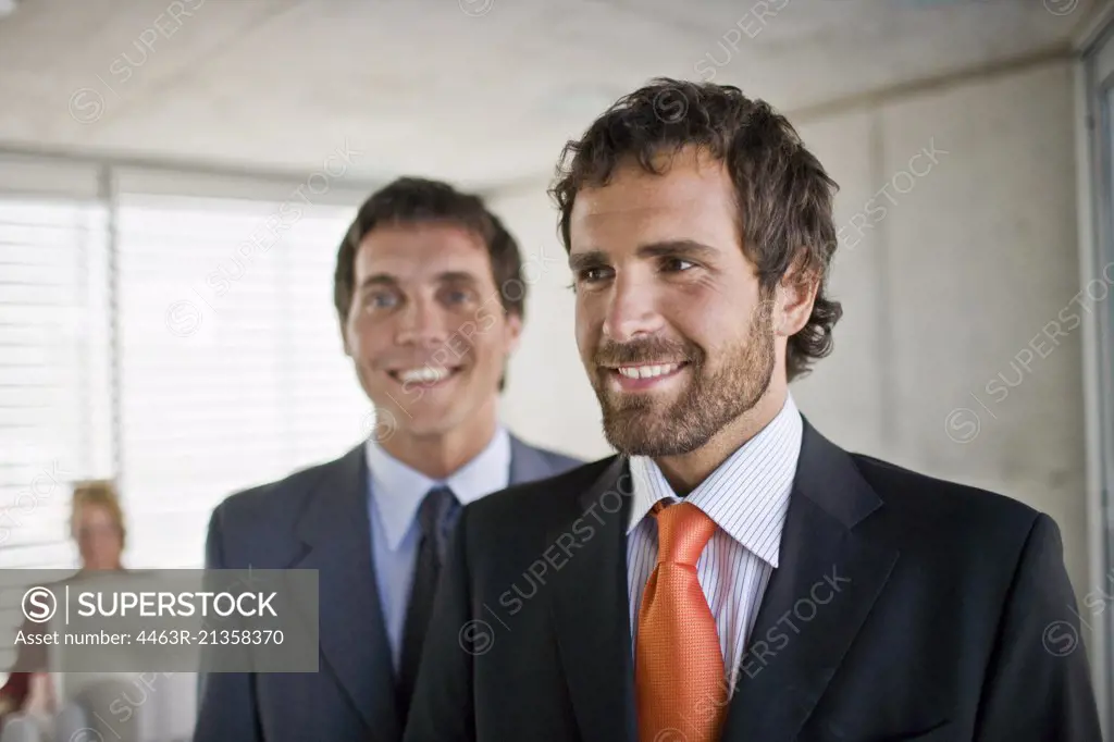 Two smiling young adult business men in an office.