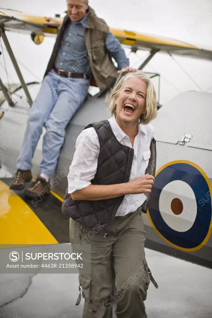 Woman walking away from airplane and laughing