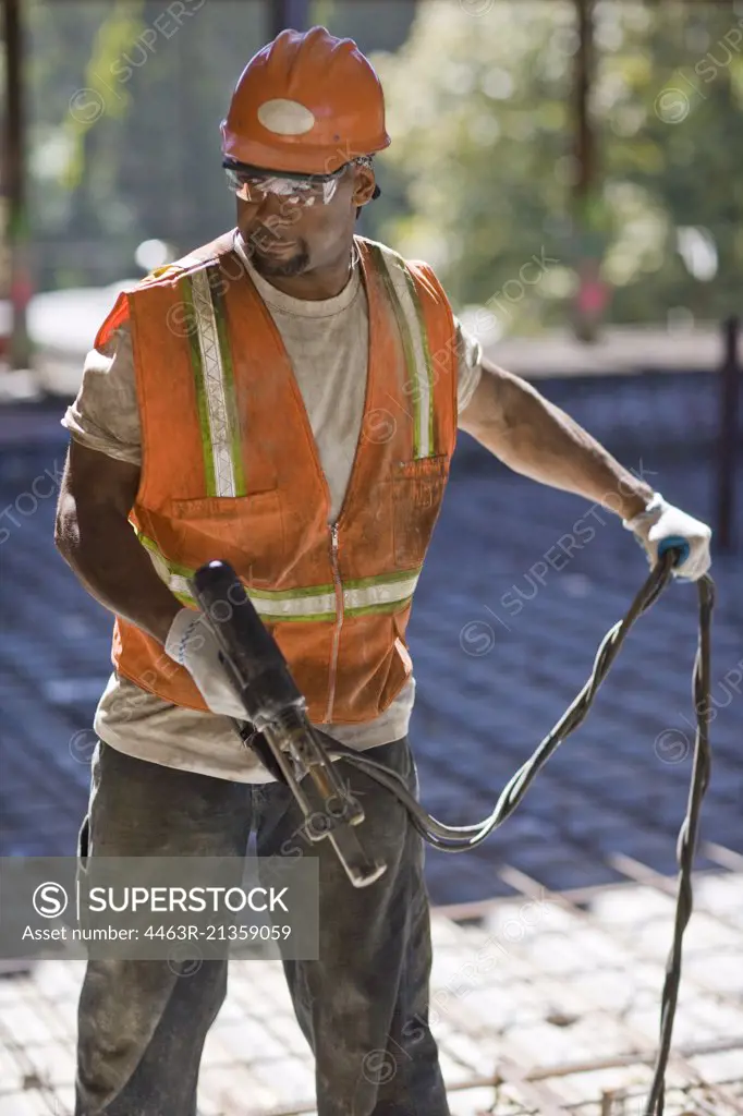 Builder on a construction site holding a drill