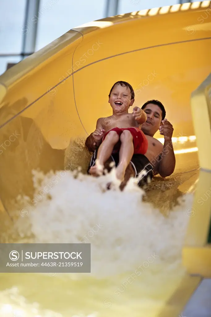 Father and son going down a waterslide together.