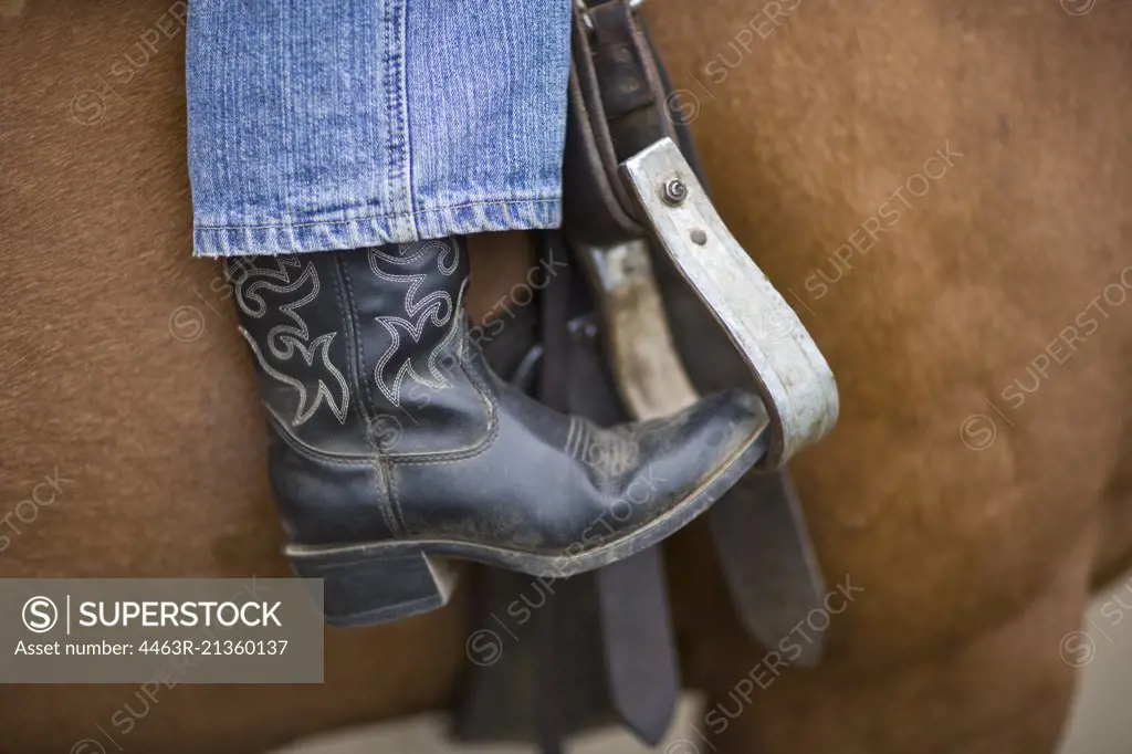 Close-up of cowboy boot in stirrup on horseback
