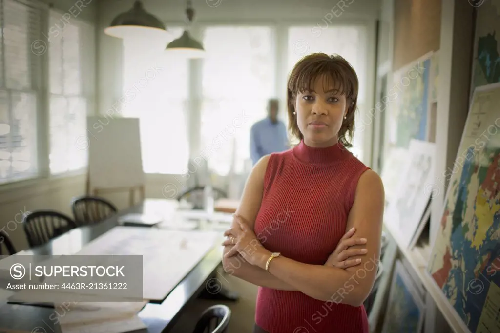 Portrait of a mid-adult woman with folded standing in a meeting room.