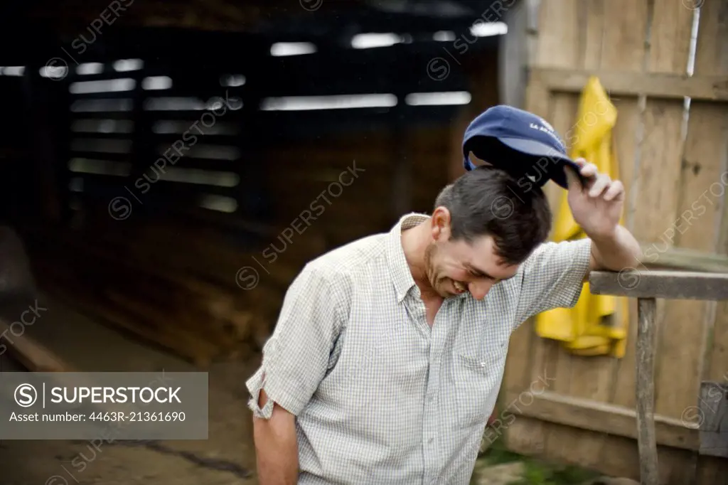 Man outside shed tipping off baseball cap