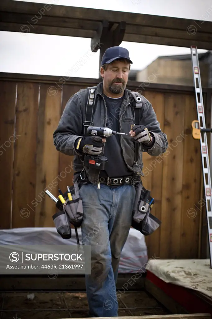Male construction worker carrying an electric drill.