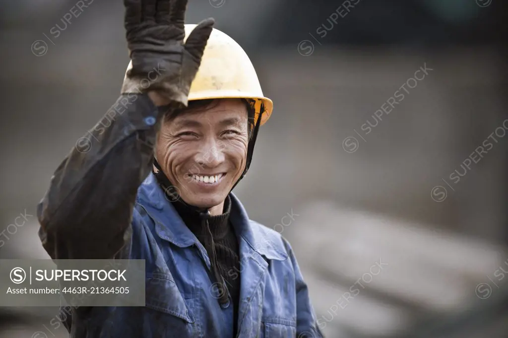 Construction worker on site,  smiling and waving