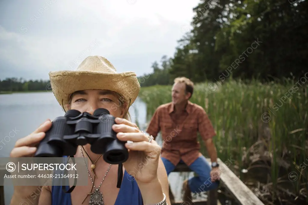 Mature woman takes a break from looking through the binoculars while bird watching at the lake.