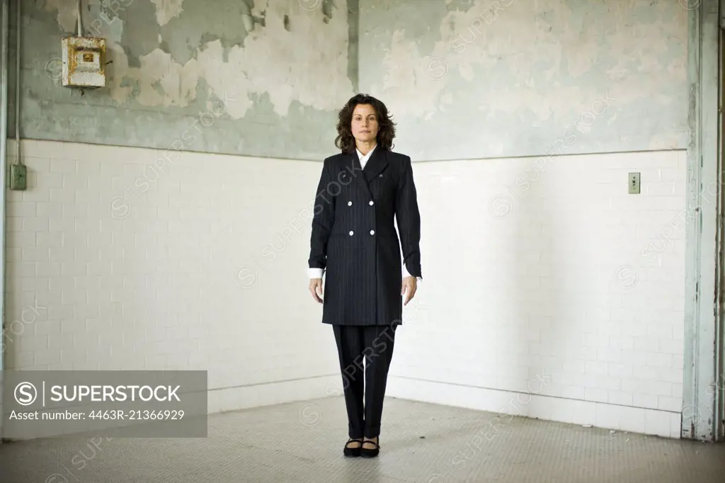 Portrait of a mid-adult business woman standing in an empty room of a derelict building.