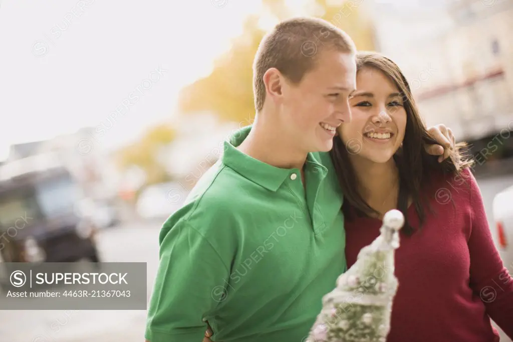 Teenage couple carrying miniature Christmas tree
