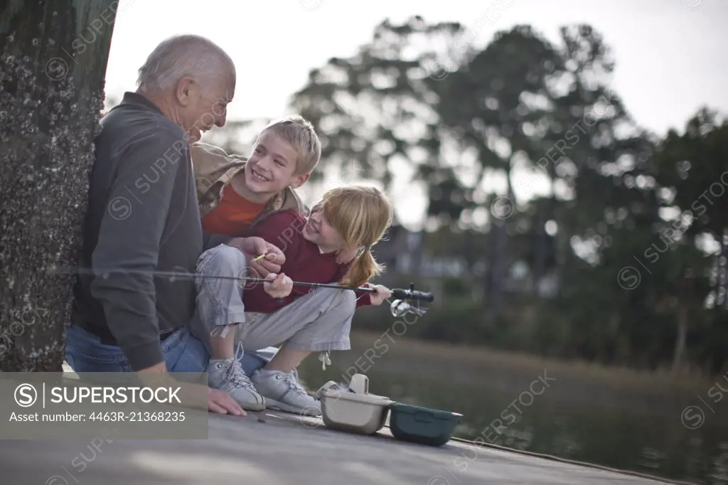 Grandfather and grandchildren fishing on pier