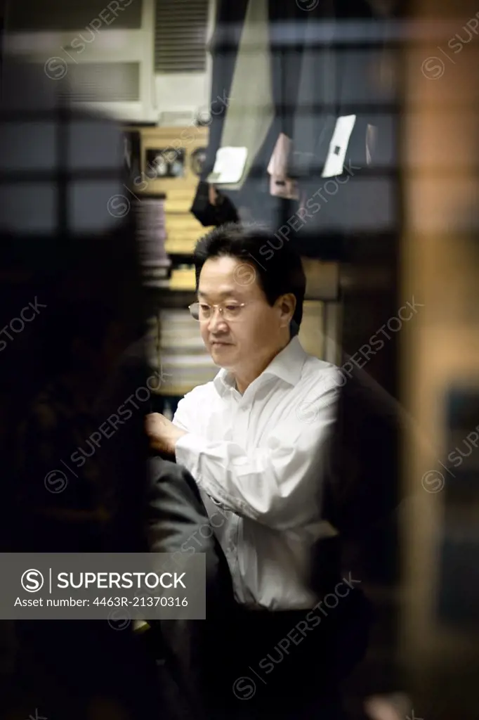 Mid-adult businessman putting on his suit jacket inside a clothing store.