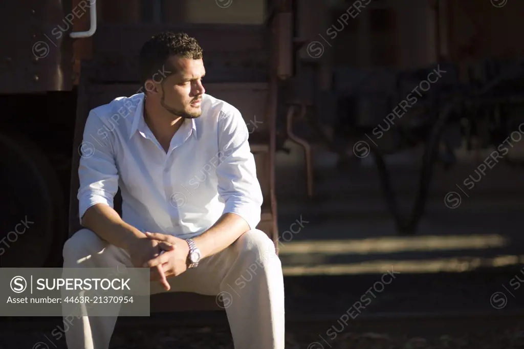 Young adult man sitting outside.