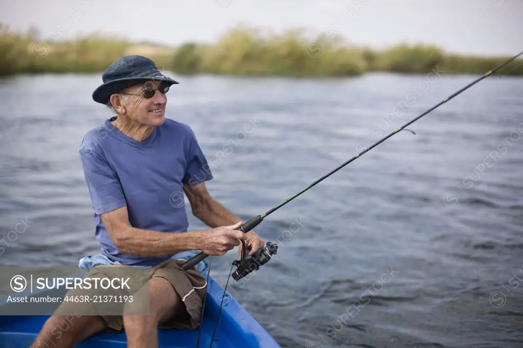 Senior man sitting in a boat fishing.