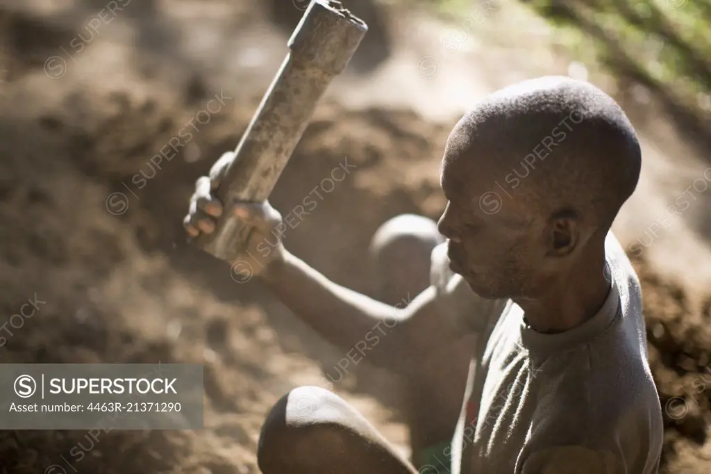 Mature adult man sitting in the garden using tools.
