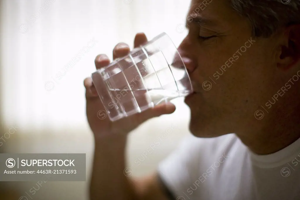 Mature man drinking a glass of water.