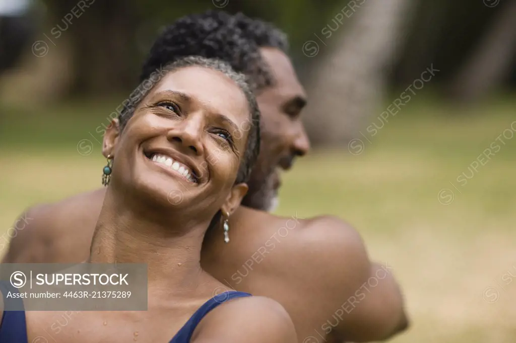 Couple sitting back to back and smiling.