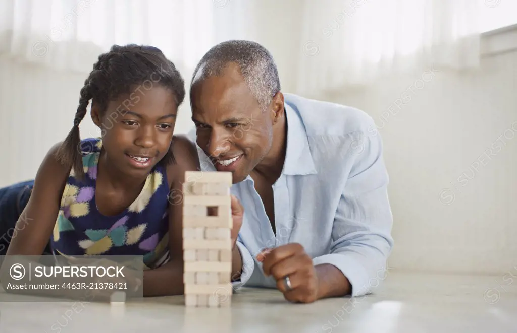 Smiling father and daughter playing with a block removal game.