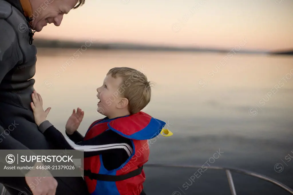 Father and young son laugh together on a boat.
