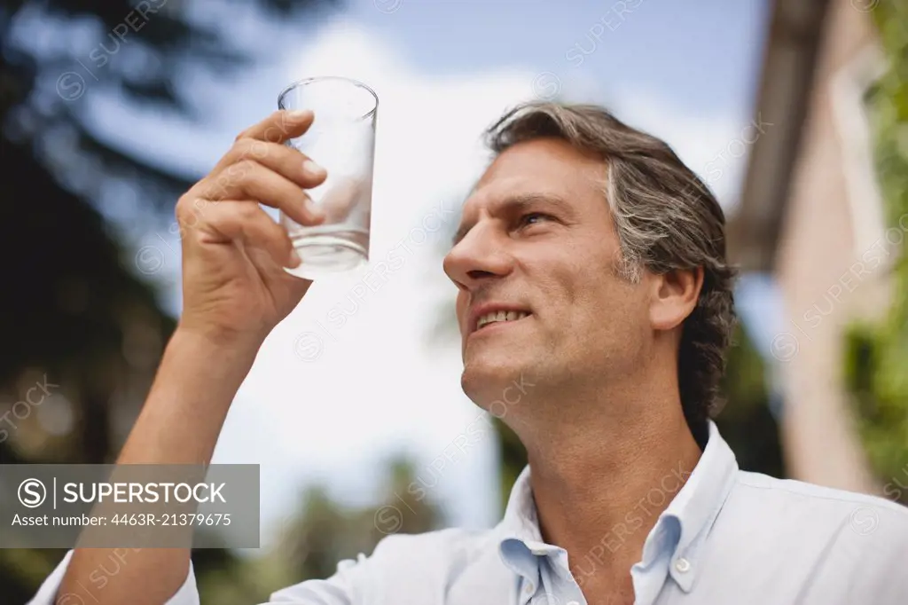 Mature man drinks a glass of water. 