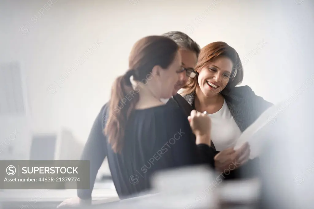 Group of professionals smile as they read a document. 