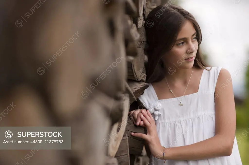 Preteen girl leans against a rock wall. 