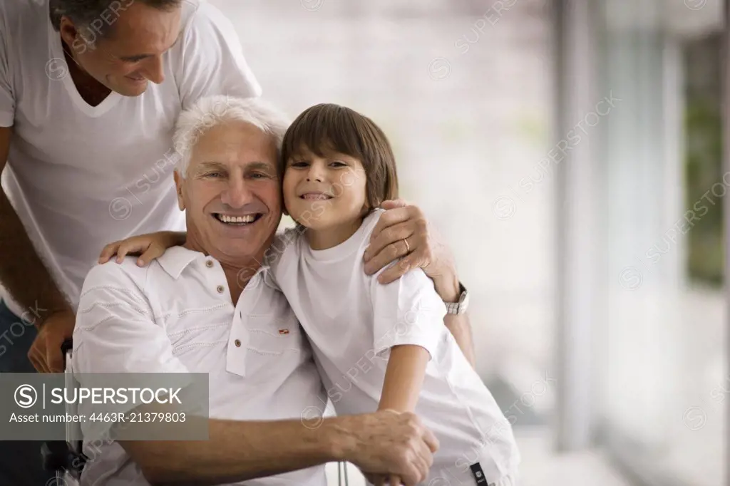 Senior man in a wheelchair hugs his young grandson.