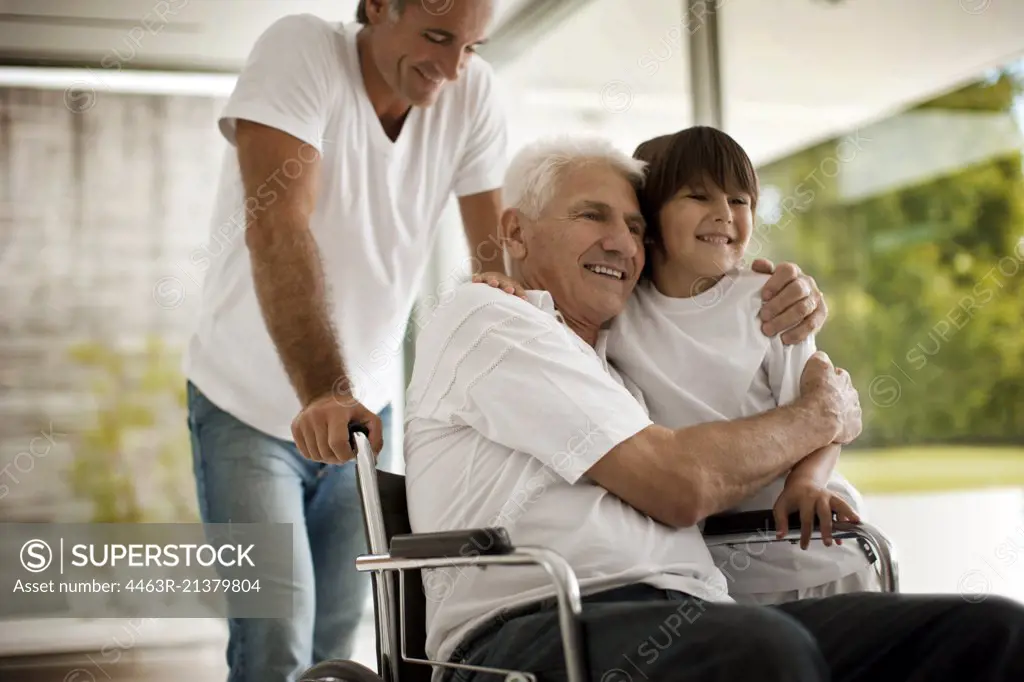 Senior man in a wheelchair hugs his young grandson.