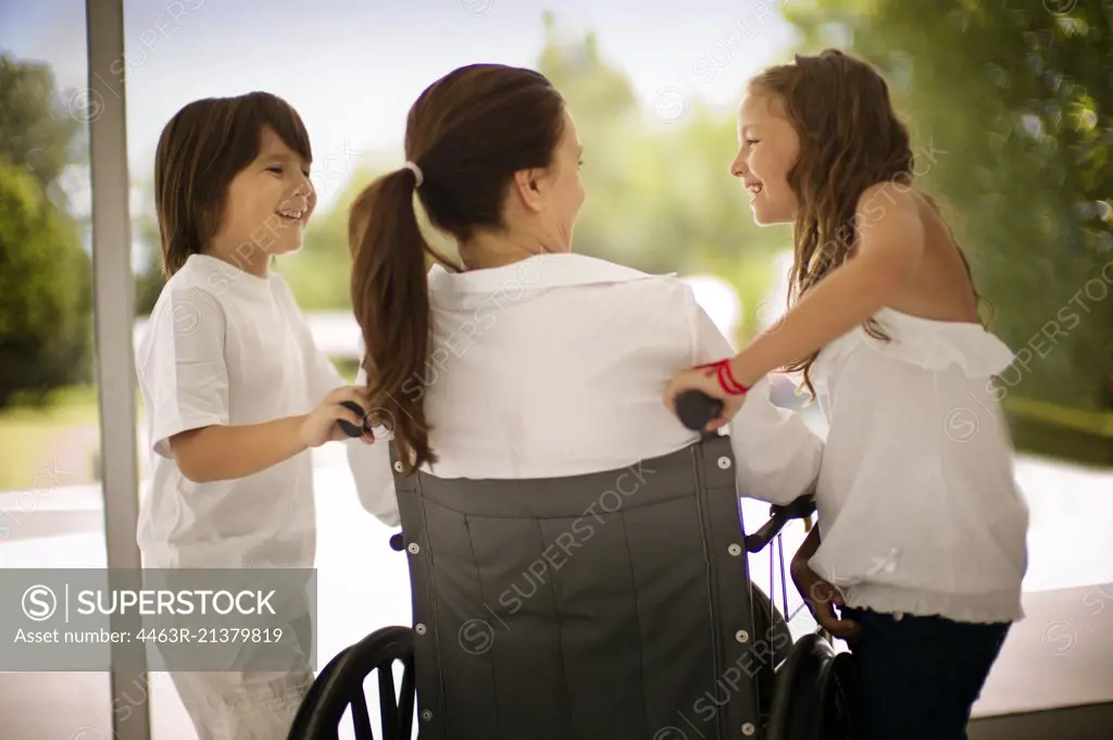 Two young children and a middle aged woman in a wheelchair. 
