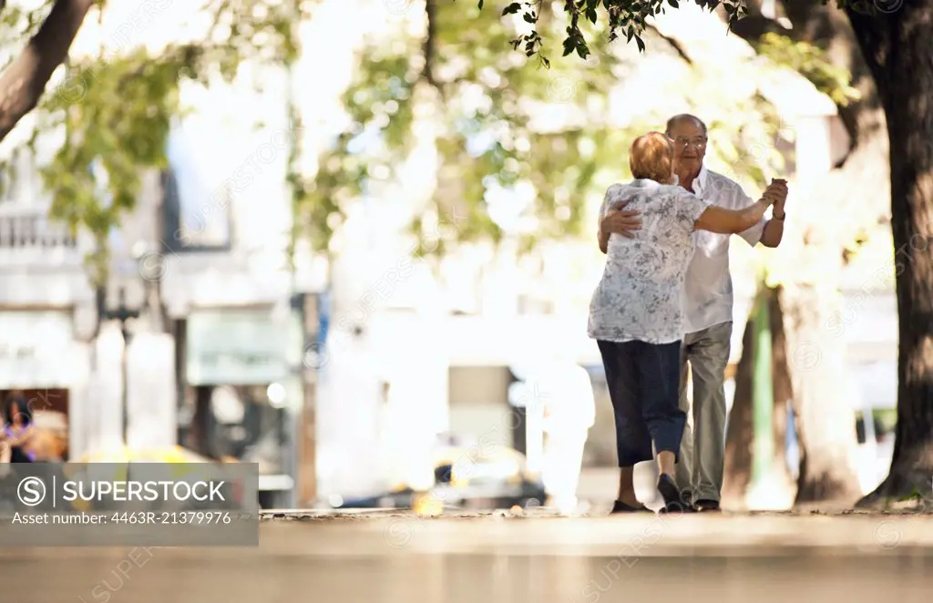 Senior couple dancing together in the street.